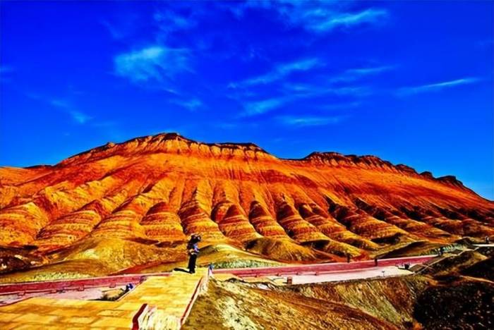 大妈踩在丹霞地貌上疯狂拍照，景区回应：地貌不可修复，禁止踩踏

