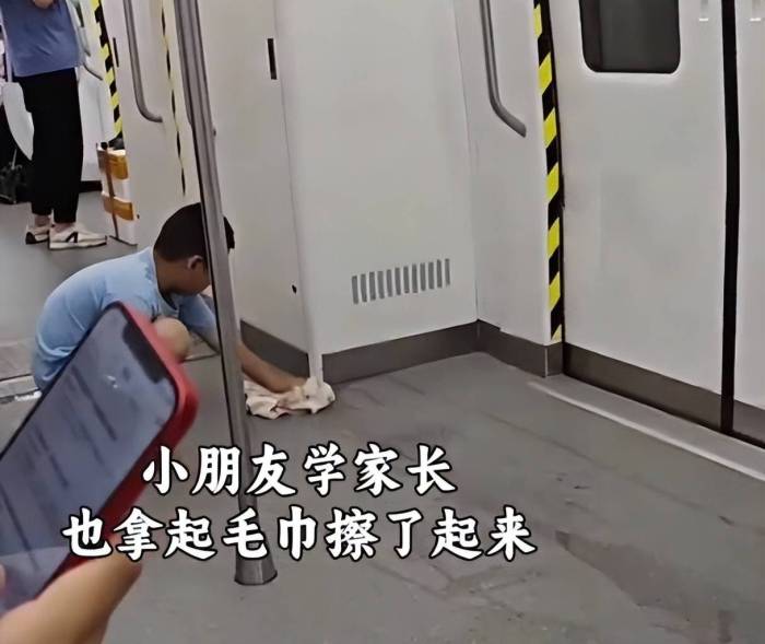 男孩饮品洒地铁家长以身作则清理